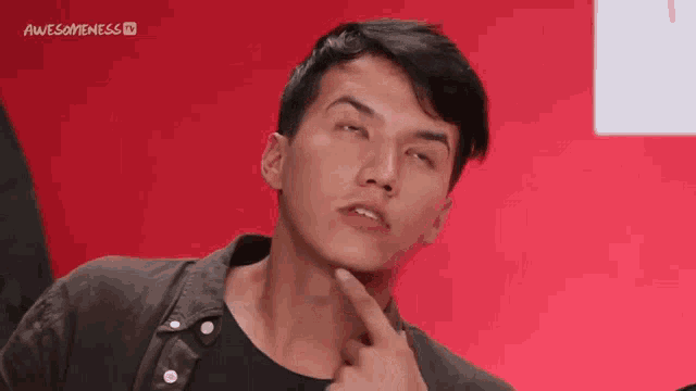 a young man is making a funny face with his finger on his chin