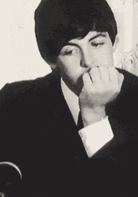 a black and white photo of a man in a suit and tie smoking a cigarette