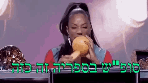 a woman is sitting at a table eating a hamburger with a foreign language behind her .