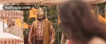 a man in a crown is standing next to a woman in a traditional dress .