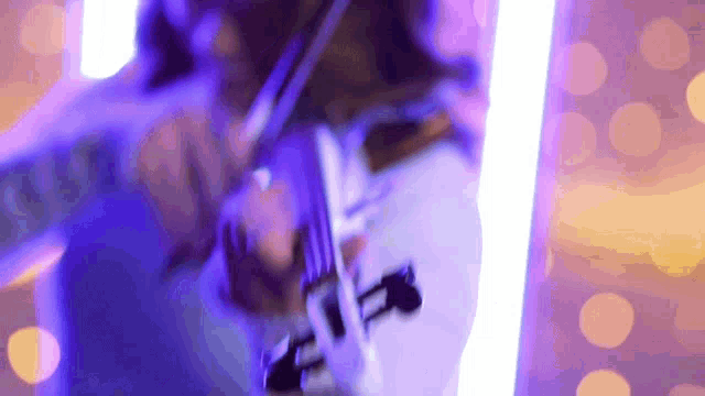 a person is playing a violin in a purple light