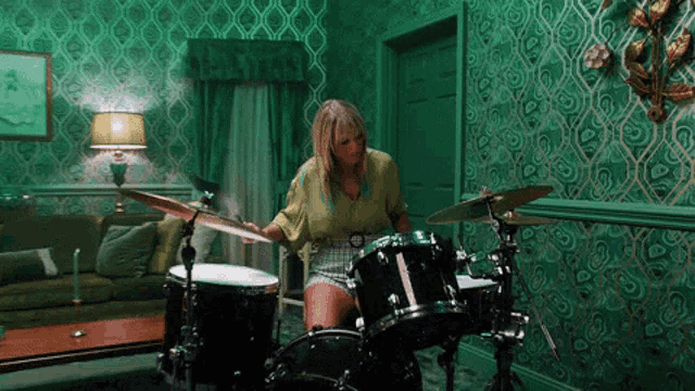 a woman plays drums in a green room