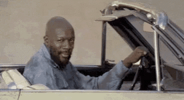 a man is sitting in the driver 's seat of a car with his hood up .