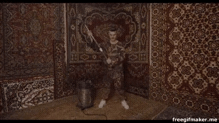 a man is standing in a room with a vacuum cleaner and a rug .