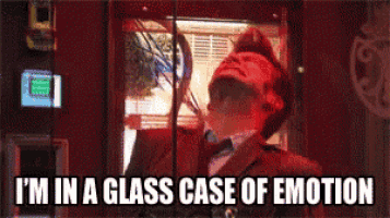 a man in a suit and tie is behind a glass with the caption i 'm in a glass case of emotion