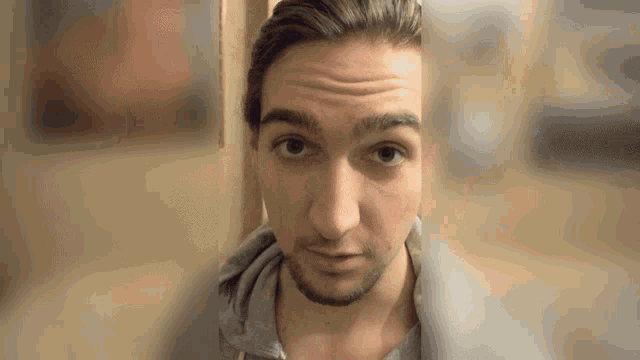 a close up of a man 's face with a gray shirt on