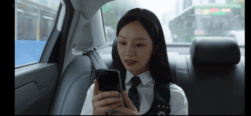 a girl sitting in the back seat of a car using her phone