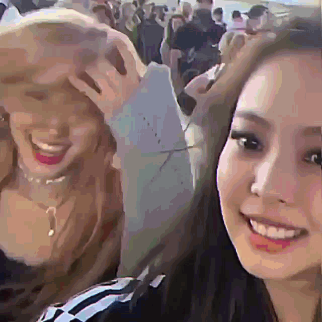 two women are smiling for a picture in front of a crowd of people