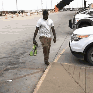 a man in a white shirt is walking down the sidewalk