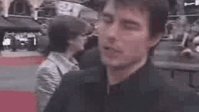 a man in a black jacket is talking to a woman in a crowd .