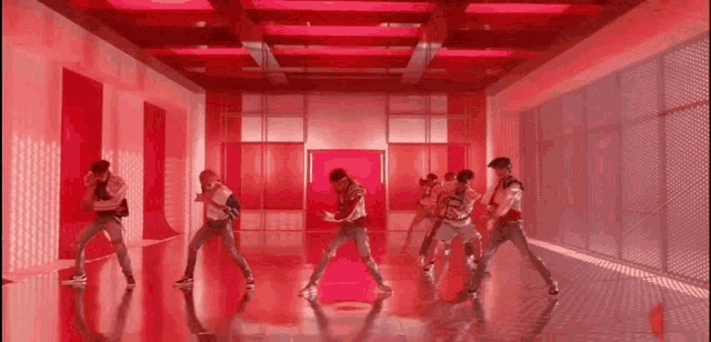 a group of men are dancing in a red room with red lights .
