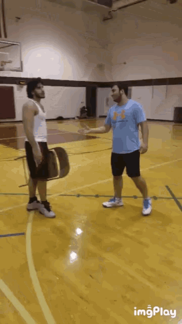a man wearing a blue under armour shirt shakes hands with another man