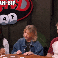 a group of people are sitting at a table with a sign that says ah-bip in the background