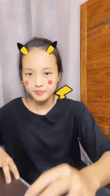 a girl with a pikachu sticker on her face looks at the camera