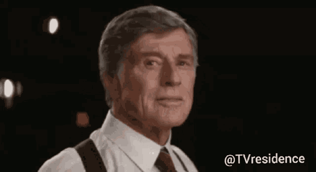 a man in a white shirt and red tie is standing in front of a black background ..