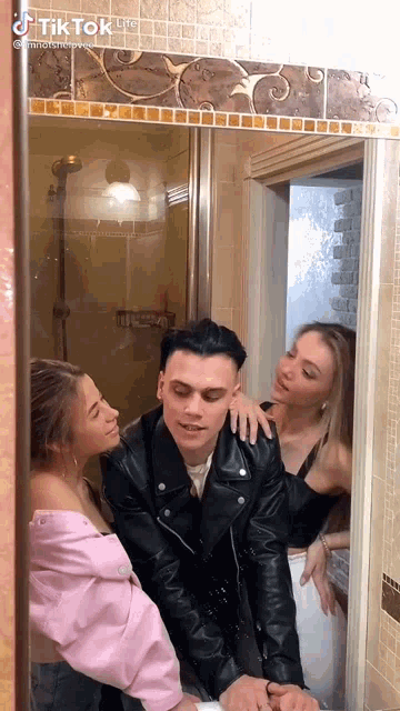 a man and two women are standing in front of a mirror .
