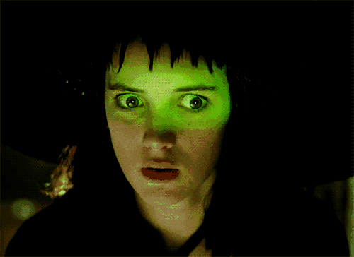 a close up of a woman 's face with green eyes and a surprised look on her face
