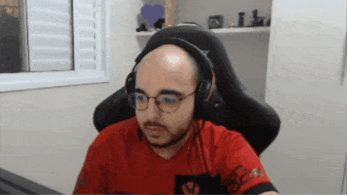 a bald man wearing glasses and headphones is sitting in front of a computer monitor