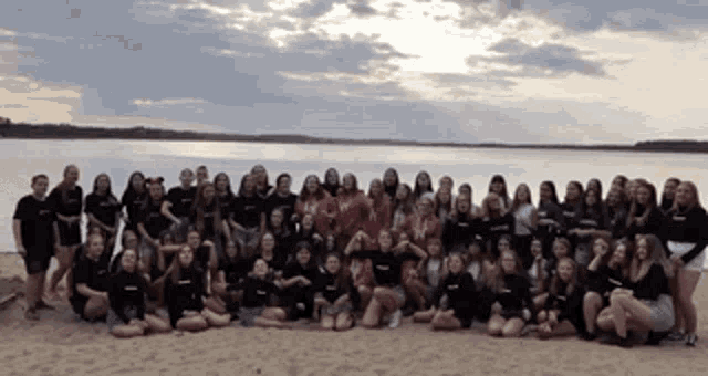 a large group of people posing for a picture on a beach
