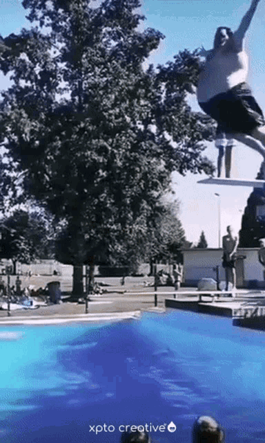 a man is jumping off a diving board into a pool with xpto creative written on the bottom