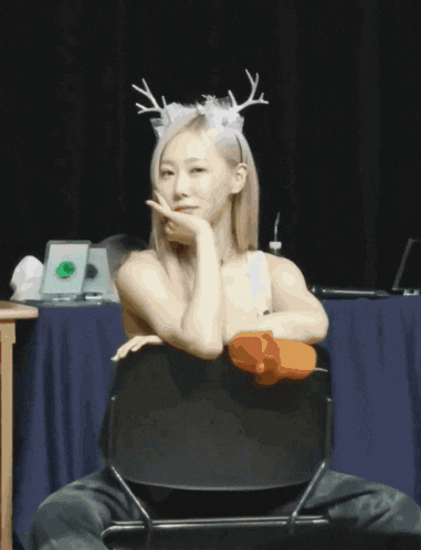 a woman with antlers on her head is sitting on a chair