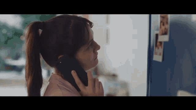 a woman in a ponytail is talking on a phone