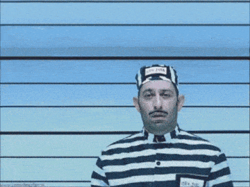 a man in a striped prison uniform is standing in front of a blue wall .
