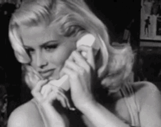 a woman with blonde hair is talking on a telephone