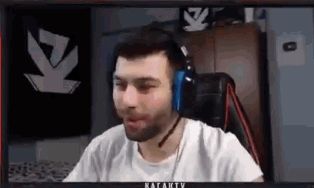 a man wearing headphones and a white shirt is sitting in front of a computer screen .