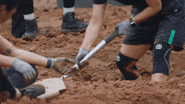 a person wearing a knee brace is digging in the dirt with a shovel