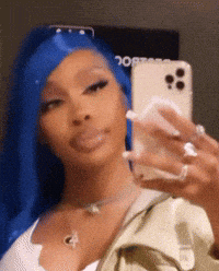 a woman with blue hair is taking a selfie with a cell phone .
