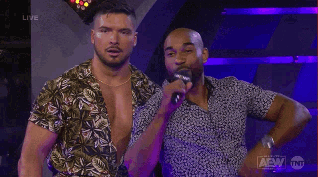two men are standing next to each other and one is holding a microphone with aew written on the bottom