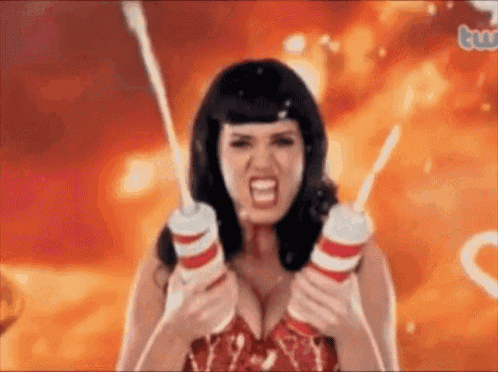 a woman in a red dress is holding two milkshakes and making a funny face .