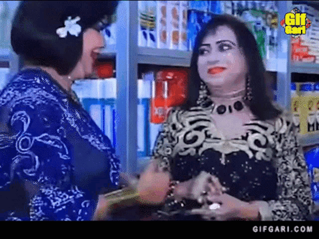 two women are standing next to each other in a store talking to each other .