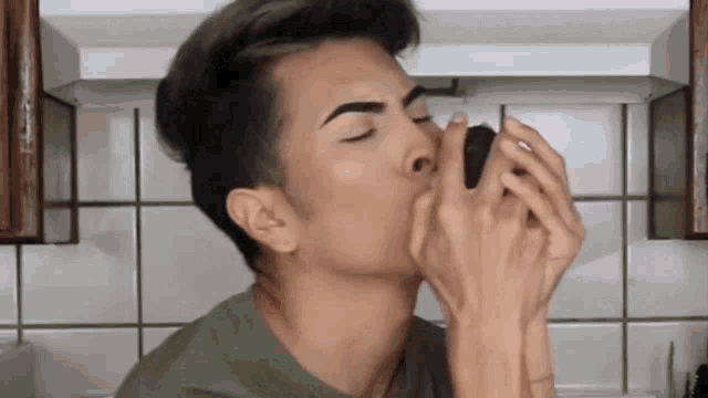a man in a green shirt is holding something in his hands and smelling it