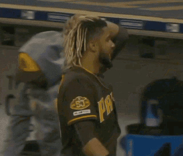 a man wearing a san diego padres jersey with dreadlocks