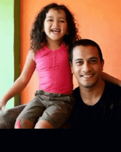 a little girl is sitting on a man 's lap