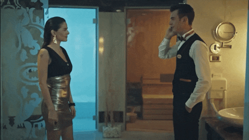 a man in a bow tie talks on a cell phone next to a woman in a black dress