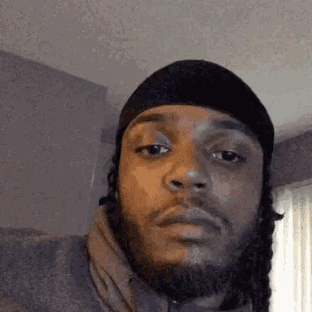 a man with a beard and dreadlocks is wearing a black headband and making a funny face .