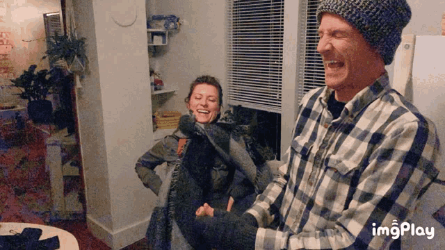 a man wearing a plaid shirt is laughing while holding a woman 's hand