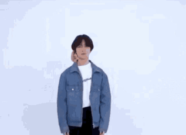 a man in a denim jacket is dancing with his arms outstretched in front of another man .