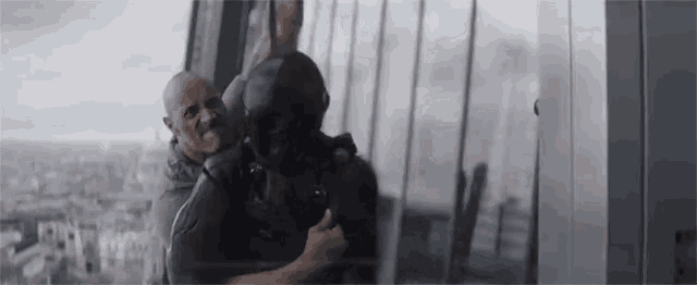 a man in a mask is holding another man in front of a building .