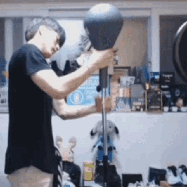 a man in a black shirt is holding a punching bag in a room .