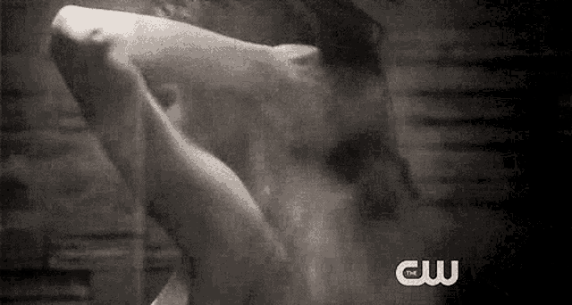 a black and white photo of a person taking a shower with the words cw written on the bottom .