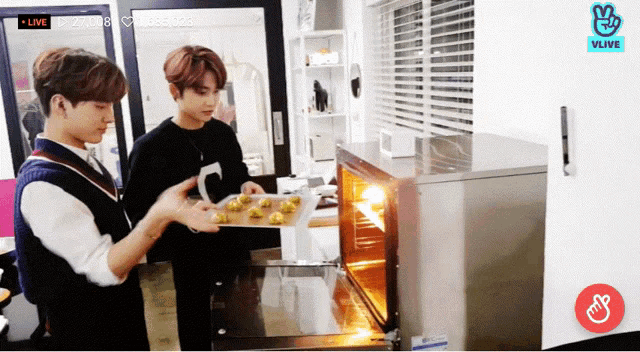 two young men are cooking in front of a vlive sign
