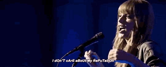 a woman is singing into a microphone while holding her head .