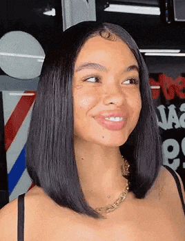 a woman with a bob hairstyle is smiling in front of a barber pole .
