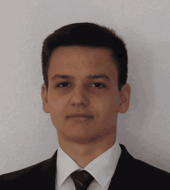 a young man wearing a suit and tie poses for a picture