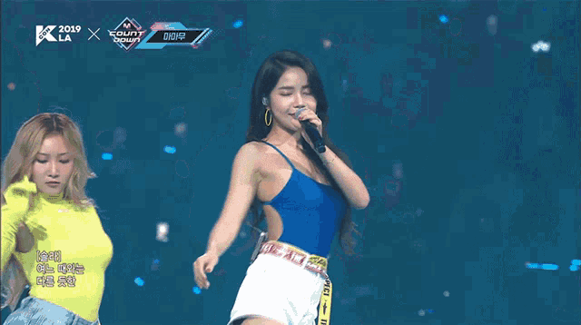 a woman singing into a microphone on a stage with the year 2019 on the bottom