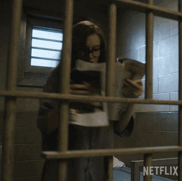 a woman behind bars in a jail cell with netflix written on the bottom right